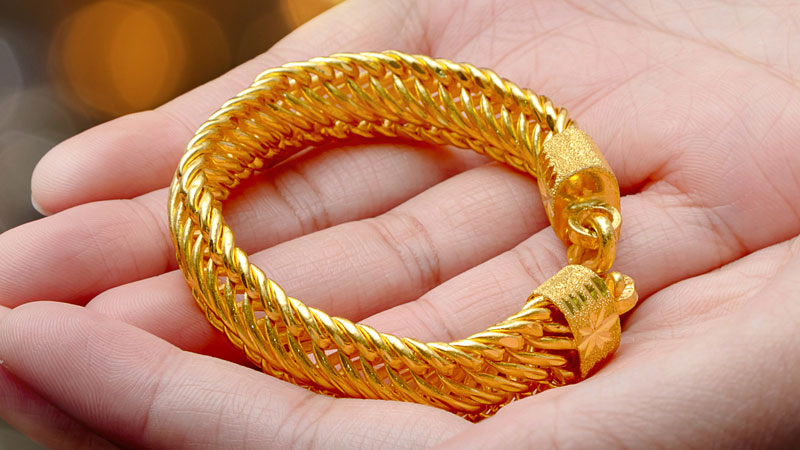 Woman holding 24k gold bracelet