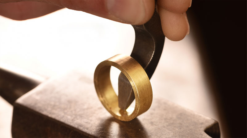 Goldsmith stamping inner band of a gold ring