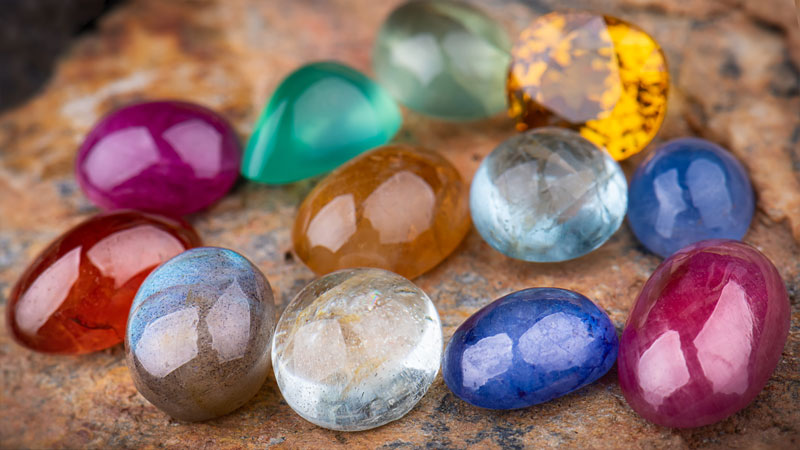 Collection of natural gemstones including  amethyst (amethyst is purple), citrine (citrine is yellow), and tourmaline (tourmaline comes in many colors)