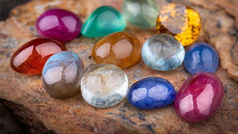 Collection of natural gemstones including  amethyst (amethyst is purple), citrine (citrine is yellow), and tourmaline (tourmaline comes in many colors)