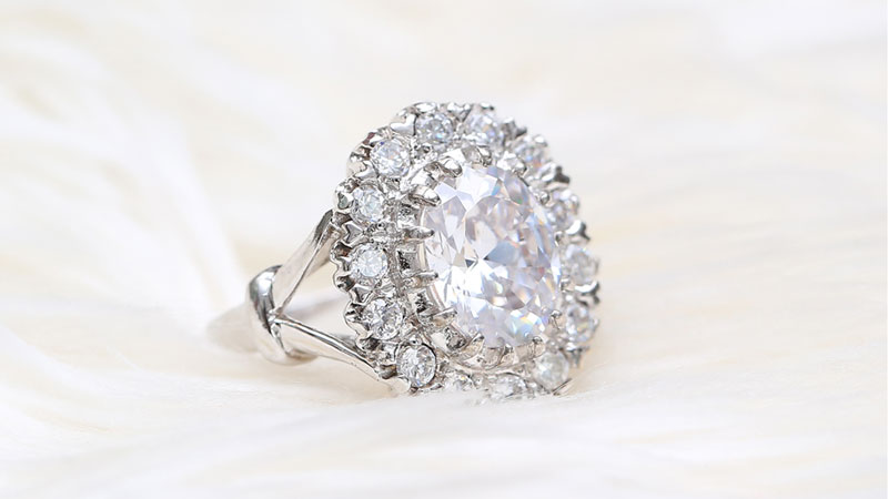 Engagement ring with an oval shape diamond center and round diamonds halo.