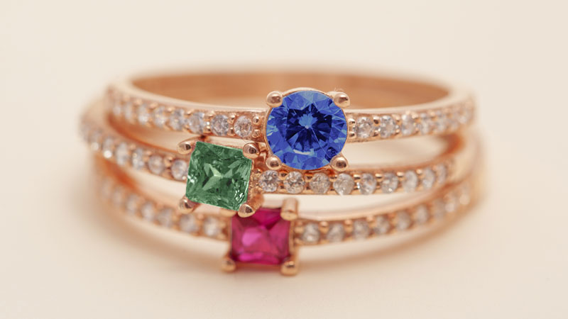 Three engagement rings set with precious stones.