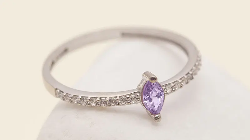 An engagement ring set with a purple fancy colored diamond.
