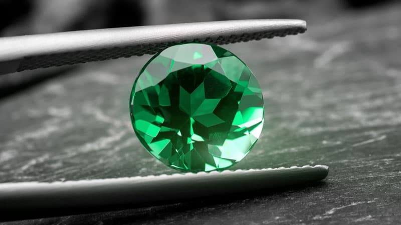 A lab created emerald type displayed in tweezers.