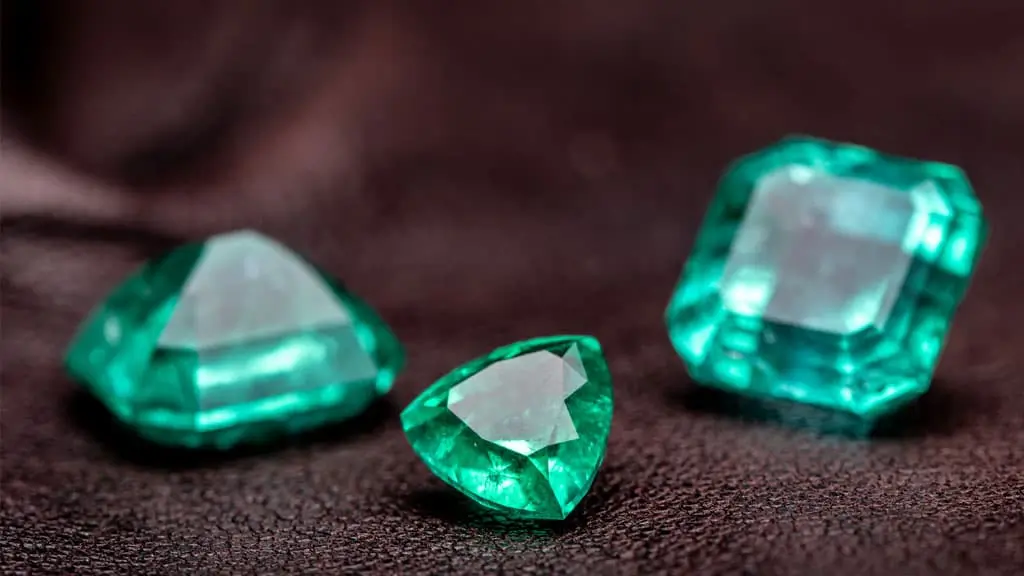 Three different types of emeralds, which are precious gemstones formed from beryl crystals.