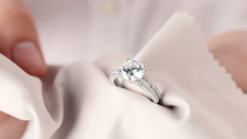 A white gold ring being polished with a microfiber cloth