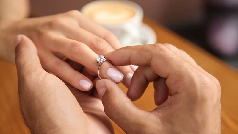 Man putting diamond jewelry on woman's finger
