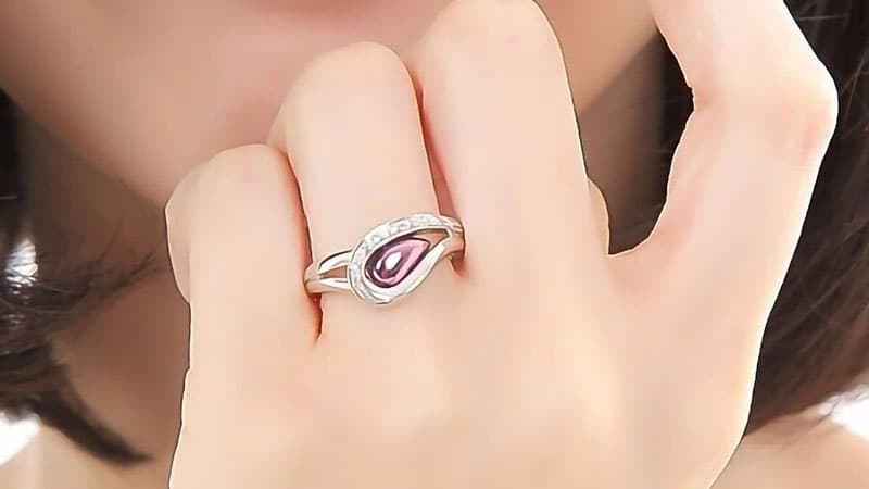 A teardrop of purple gold lies inside a white ring setting